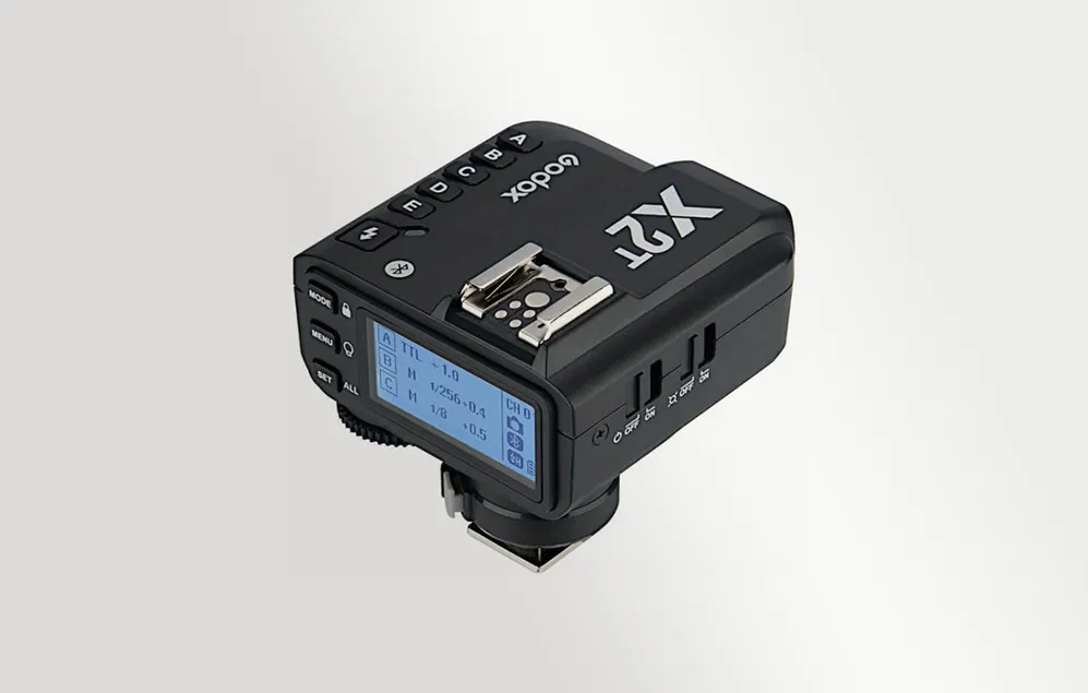Declanșatorul radio Godox X2T negru, prezentat dintr-un unghi, cu ecranul LCD retroiluminat