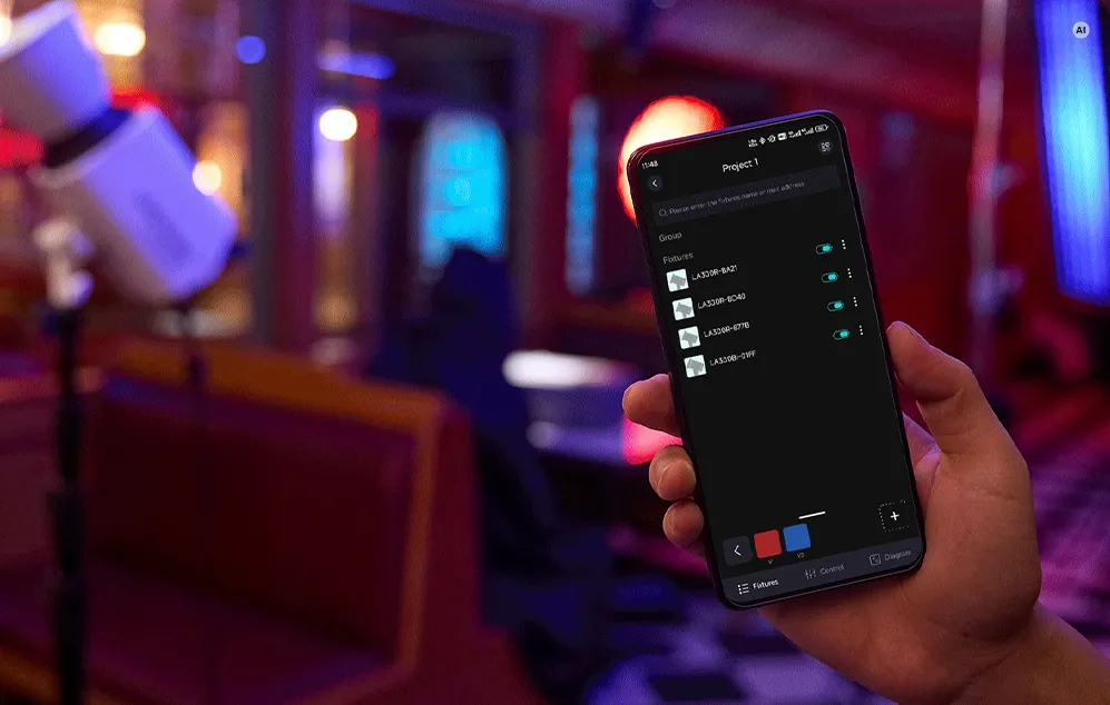 O mână care ține un smartphone cu o aplicație deschisă pentru controlul în grup al lămpilor LED Godox într-un spațiu slab iluminat.