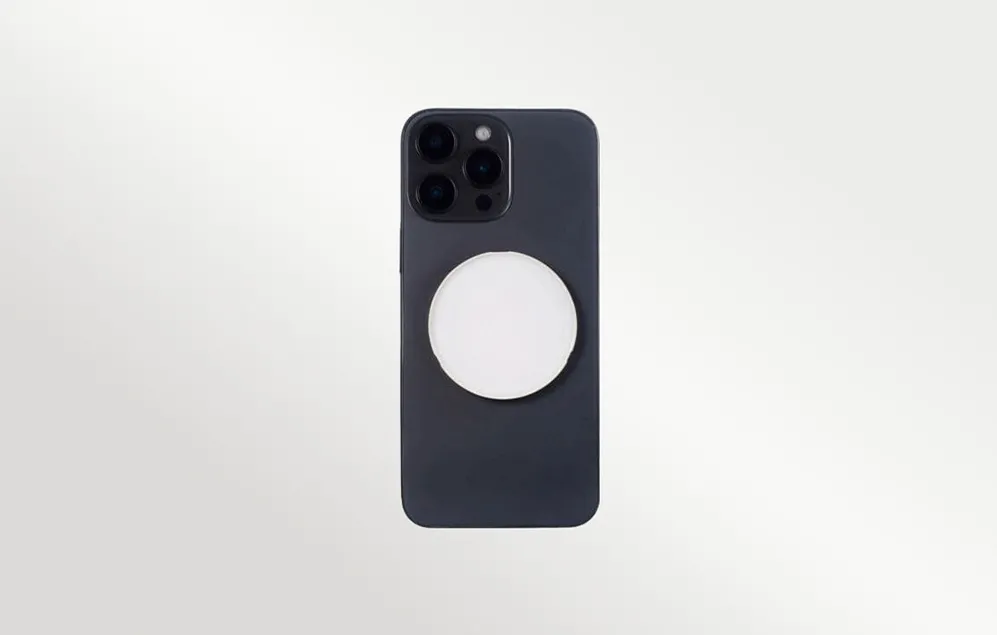 O lampă LED Godox albă, magnetică, atașată pe partea din spate a unui smartphone negru, privită direct din spate