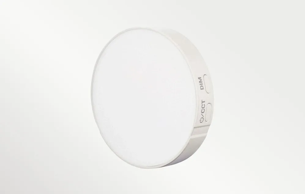 O lampă LED Godox rotundă, albă, cu butoane de control DIM și CCT vizibile pe partea laterală a carcasei