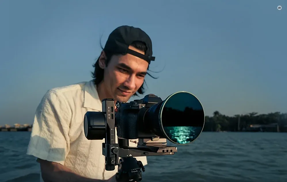 Un bărbat filmează lângă apă cu o cameră montată pe un gimbal, echipată cu un filtru de densitate neutră Freewell