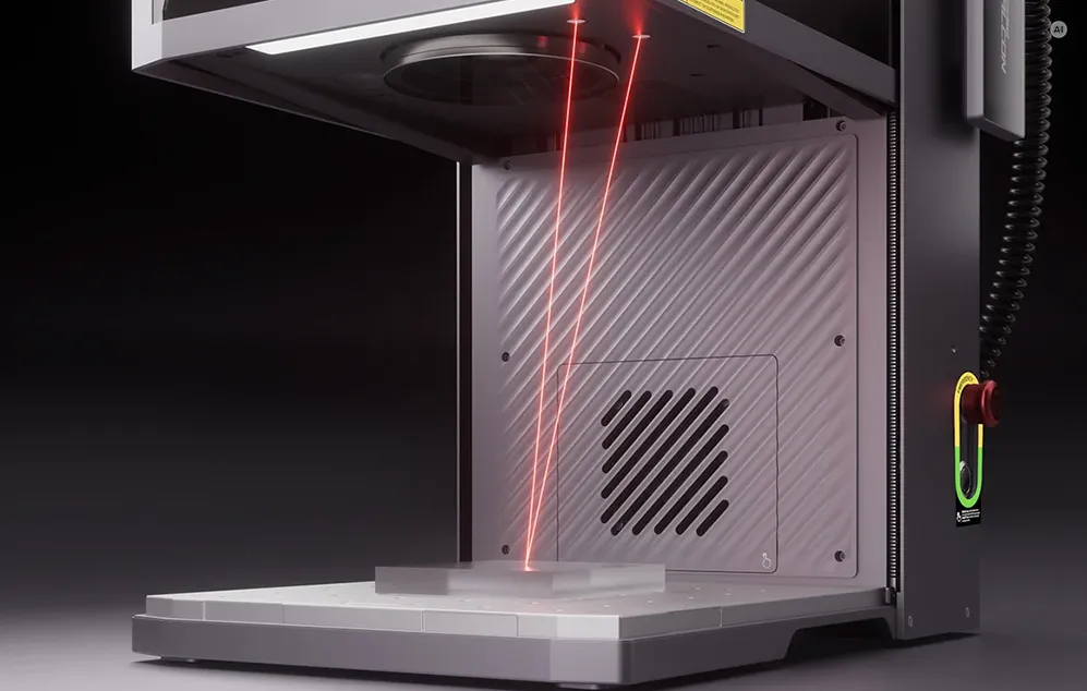 Raze roșii de lumină în interiorul unui gravor laser deschis, îndreptate către materialul așezat pe bază.
