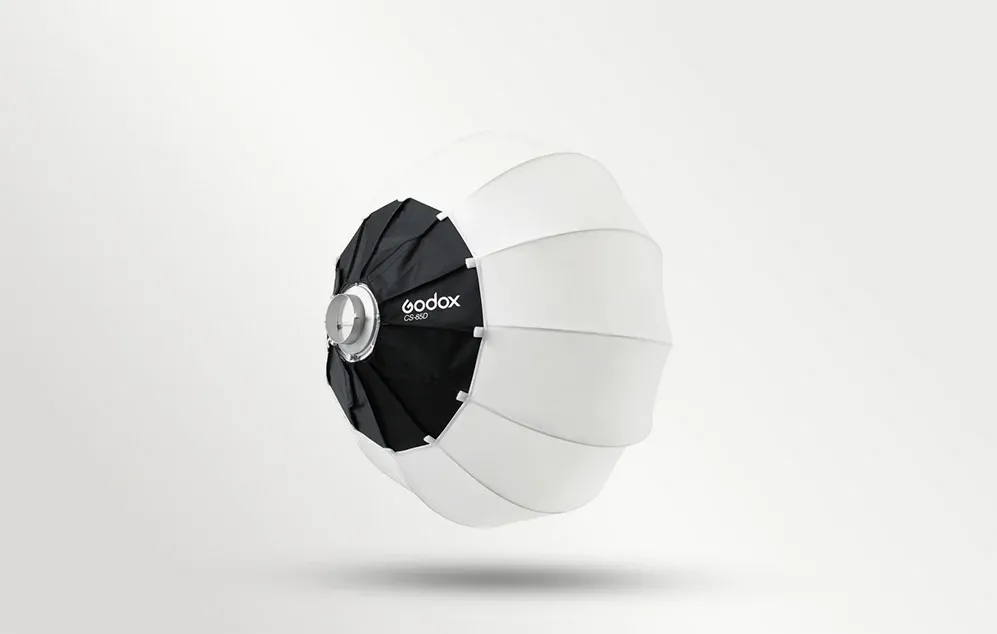 O softbox sferică rotundă, alb-negru, cu logo-ul Godox, prezentată din profil pe un fundal deschis, cu o umbră subtilă.
