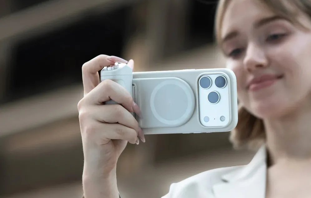 O femeie ținând un smartphone cu suportul atașat și făcând o fotografie în aer liber