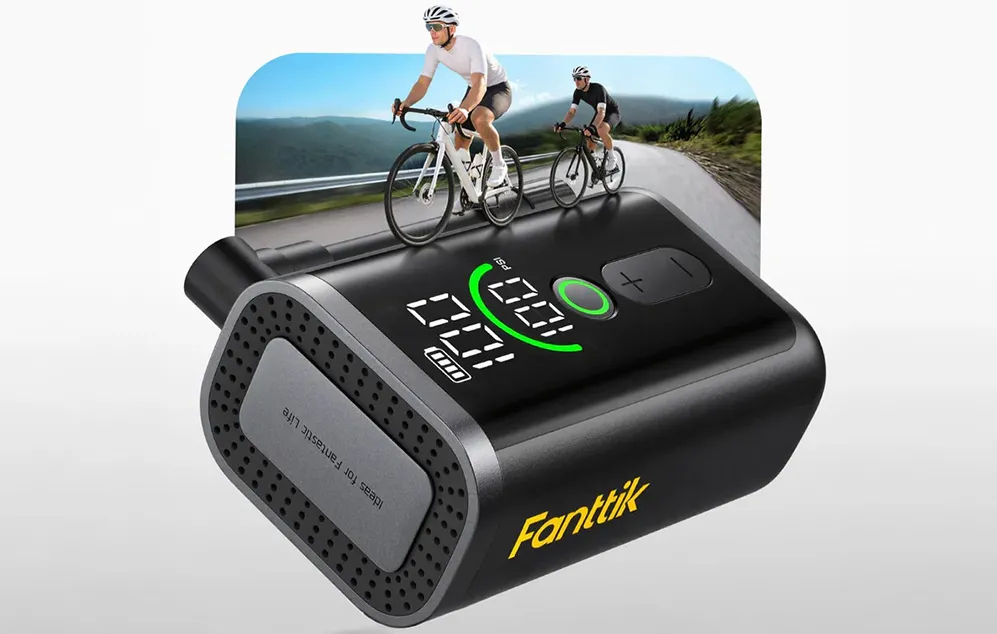 Pompa compactă Fanttik pe fundalul cicliștilor care pedalează, afișând un manometru digital și un indicator al nivelului de încărcare a bateriei