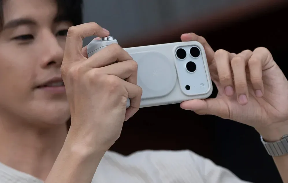 O persoană ținând un smartphone cu un suport și făcând o fotografie în poziție orizontală